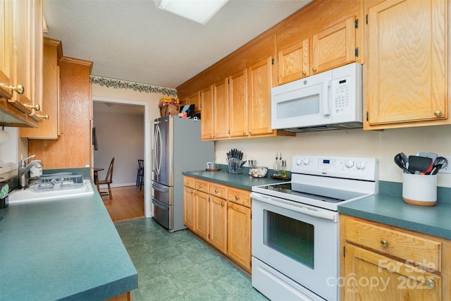 kitchen featuring sink, a textured ceiling, and white appliances