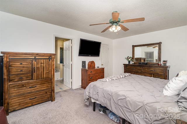 bedroom featuring light carpet, a textured ceiling, ceiling fan, and ensuite bath