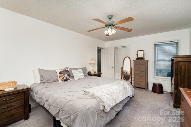 carpeted bedroom with ceiling fan and a textured ceiling