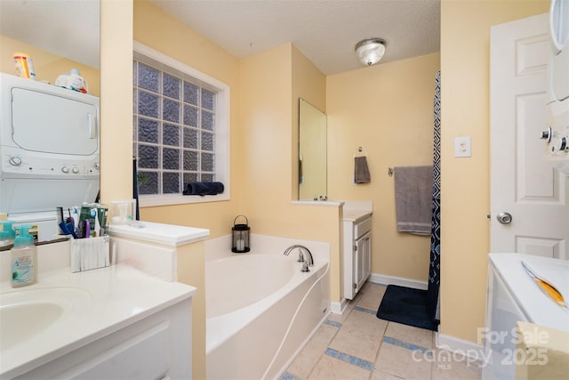 bathroom featuring stacked washer and dryer, tile patterned floors, a textured ceiling, vanity, and a washtub