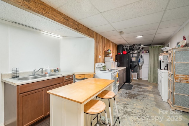 kitchen with a breakfast bar, white electric range, sink, concrete floors, and a drop ceiling