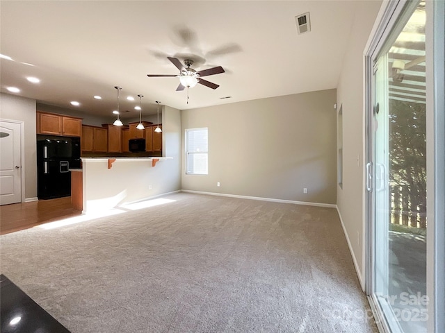 unfurnished living room with light carpet and ceiling fan