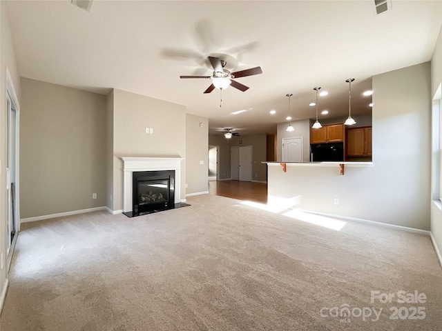 unfurnished living room featuring light carpet and ceiling fan