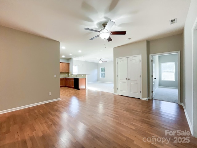 unfurnished living room featuring sink, light hardwood / wood-style floors, and ceiling fan