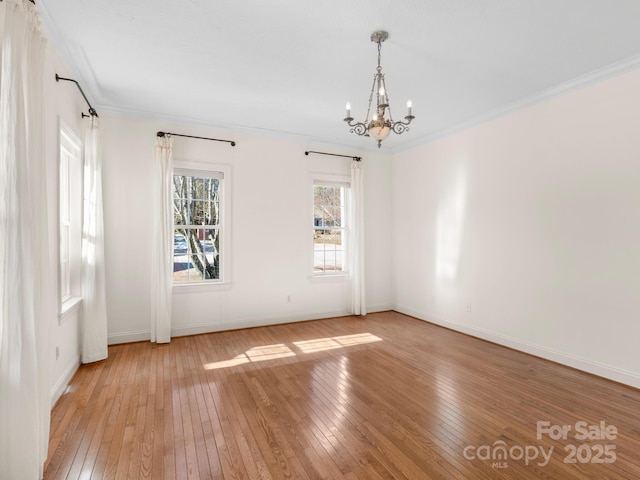 empty room featuring crown molding, a chandelier, and light hardwood / wood-style flooring