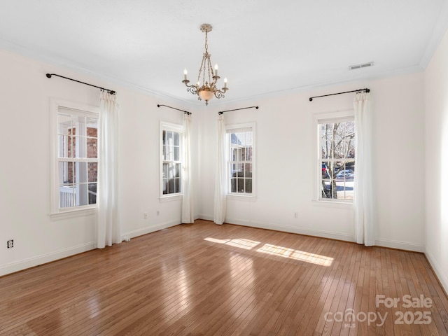 spare room featuring crown molding, wood-type flooring, and a chandelier