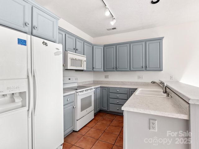 kitchen featuring sink, gray cabinetry, light tile patterned floors, kitchen peninsula, and white appliances