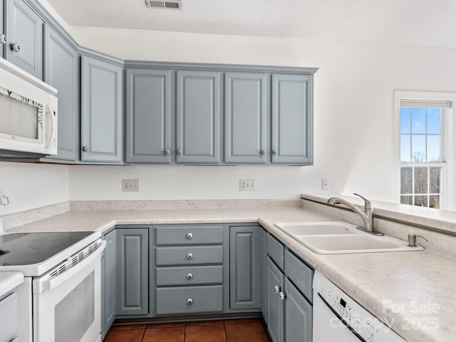 kitchen featuring gray cabinetry, sink, white appliances, and dark tile patterned flooring