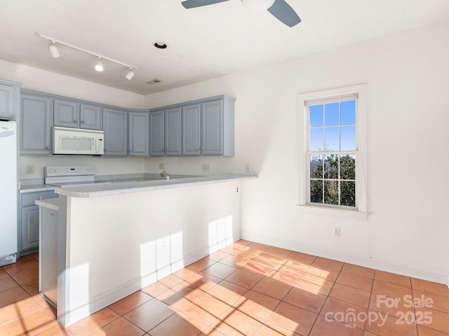 kitchen with light tile patterned flooring, white appliances, kitchen peninsula, and ceiling fan