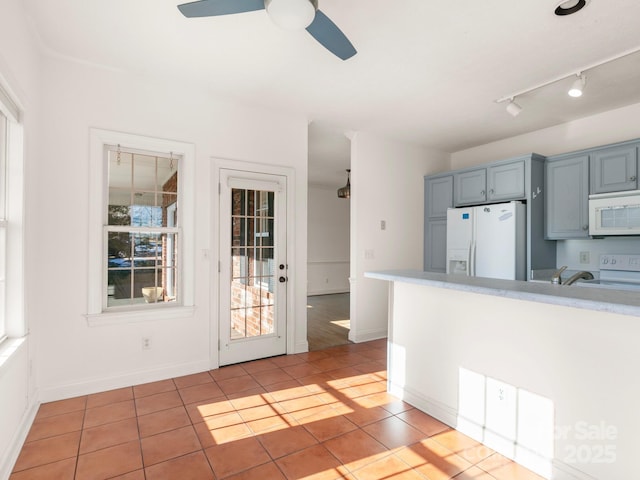 kitchen with sink, white appliances, light tile patterned floors, gray cabinets, and ceiling fan