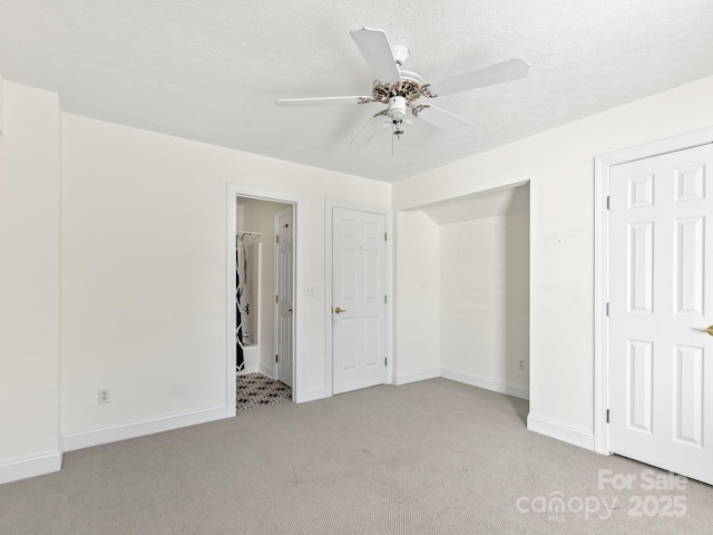 unfurnished bedroom featuring light carpet, a textured ceiling, and ceiling fan