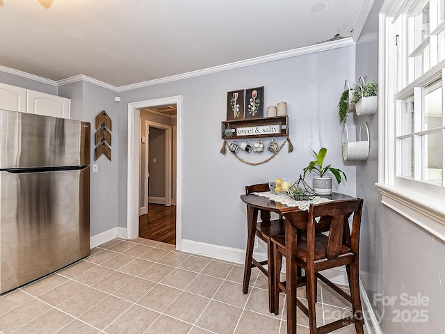 kitchen with light tile patterned floors, white cabinets, crown molding, and stainless steel refrigerator