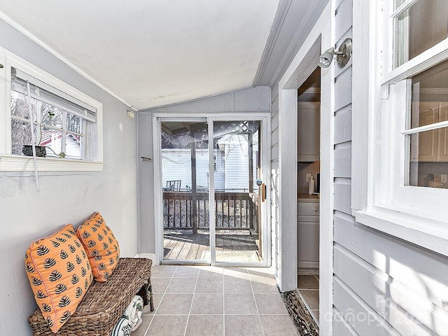 living area with vaulted ceiling, ornamental molding, and light tile patterned floors