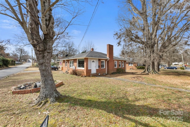 view of side of property featuring brick siding, a yard, and a chimney