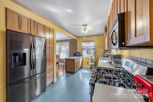 kitchen featuring baseboards, appliances with stainless steel finishes, light countertops, crown molding, and a sink