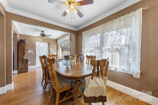 dining area with light wood-type flooring, crown molding, and baseboards