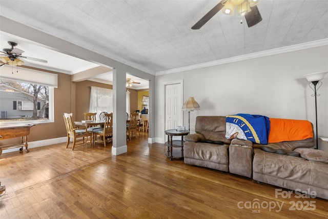 living room with a ceiling fan, baseboards, wood finished floors, and ornamental molding