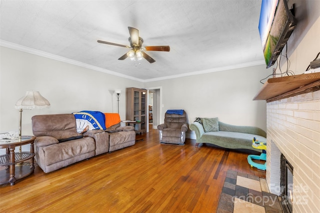 living room with a ceiling fan, crown molding, a fireplace, and wood finished floors