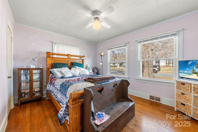 bedroom featuring baseboards, visible vents, ceiling fan, wood finished floors, and crown molding