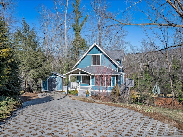 view of front of home featuring covered porch and a shed