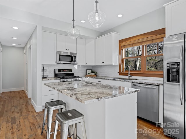 kitchen featuring pendant lighting, white cabinets, a center island, stainless steel appliances, and sink