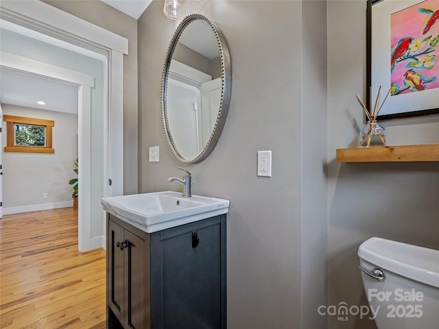 bathroom featuring wood-type flooring, toilet, and vanity