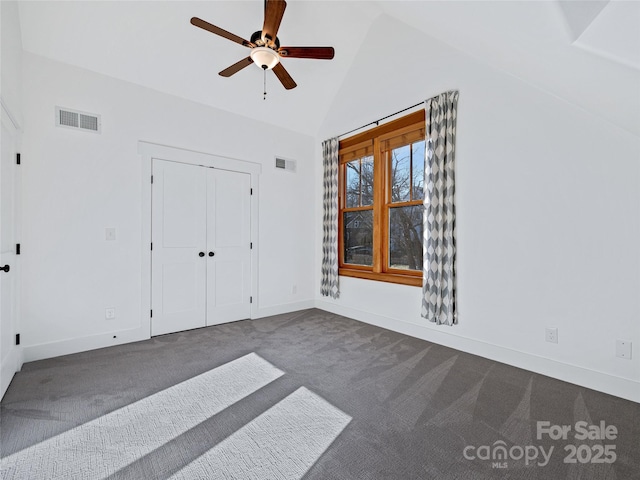 unfurnished bedroom featuring dark carpet, a closet, high vaulted ceiling, and ceiling fan