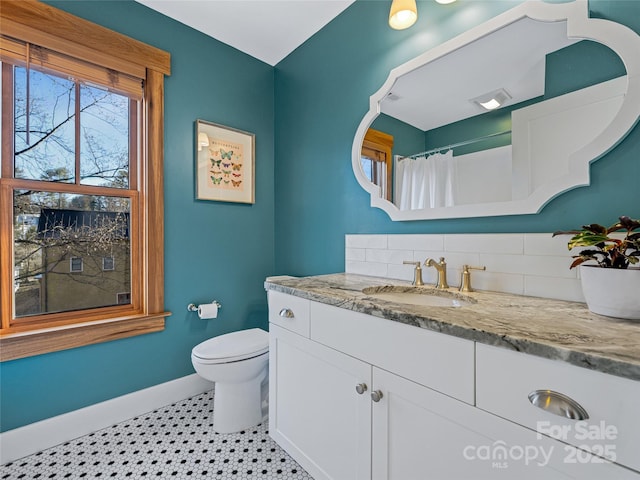 bathroom featuring vanity, toilet, and tasteful backsplash