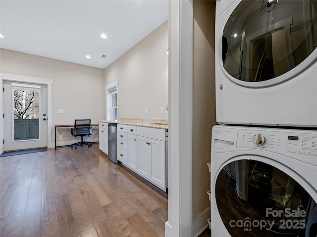 laundry room with light hardwood / wood-style flooring and stacked washer and dryer