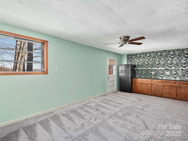 carpeted empty room featuring a textured ceiling and ceiling fan