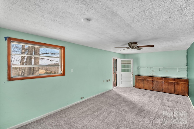 unfurnished living room with light carpet, ceiling fan, and a textured ceiling