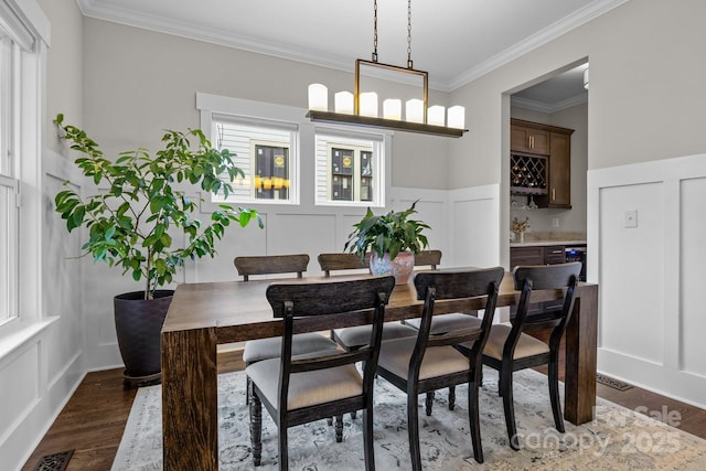 dining area featuring bar, ornamental molding, and dark hardwood / wood-style floors