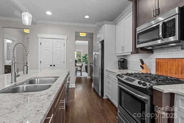 kitchen with white cabinets, dark brown cabinetry, stainless steel appliances, sink, and crown molding