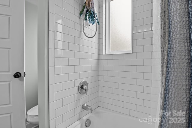 bathroom featuring tiled shower / bath combo and toilet