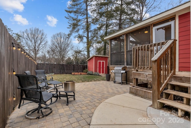 view of patio featuring a sunroom, area for grilling, and a shed