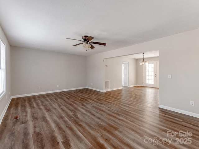 spare room featuring ceiling fan with notable chandelier and dark hardwood / wood-style flooring