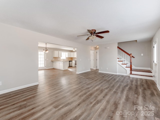 unfurnished living room with ceiling fan with notable chandelier and wood-type flooring