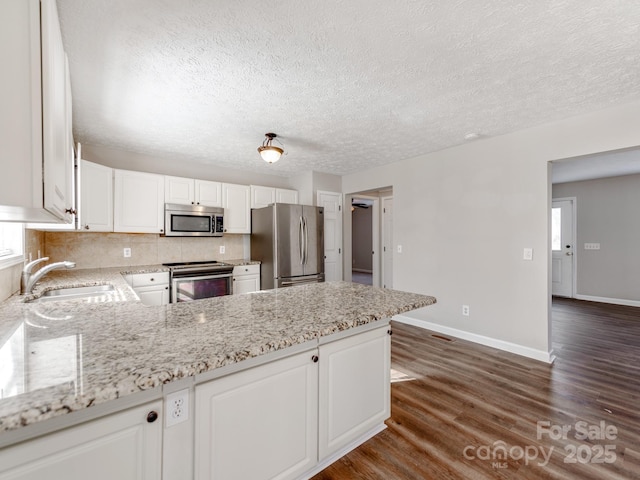 kitchen with white cabinetry, light stone countertops, and stainless steel appliances