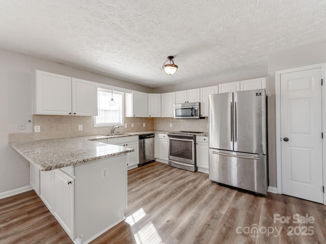 kitchen featuring stainless steel appliances, sink, white cabinets, and light hardwood / wood-style flooring