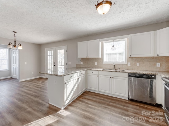 kitchen with stainless steel dishwasher, kitchen peninsula, and white cabinets