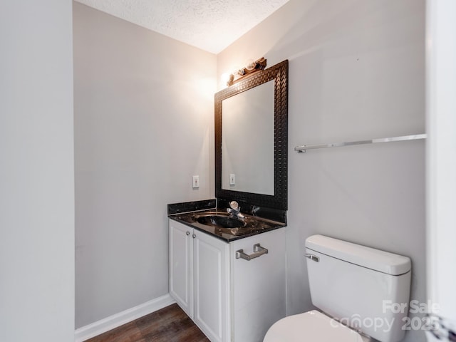 bathroom with vanity, wood-type flooring, a textured ceiling, and toilet