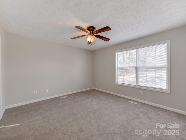 empty room with ceiling fan, light colored carpet, and a textured ceiling