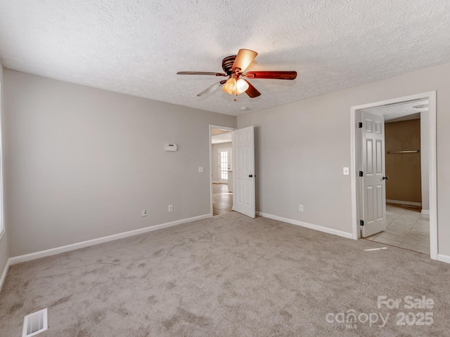 unfurnished bedroom featuring ceiling fan, light colored carpet, and a textured ceiling