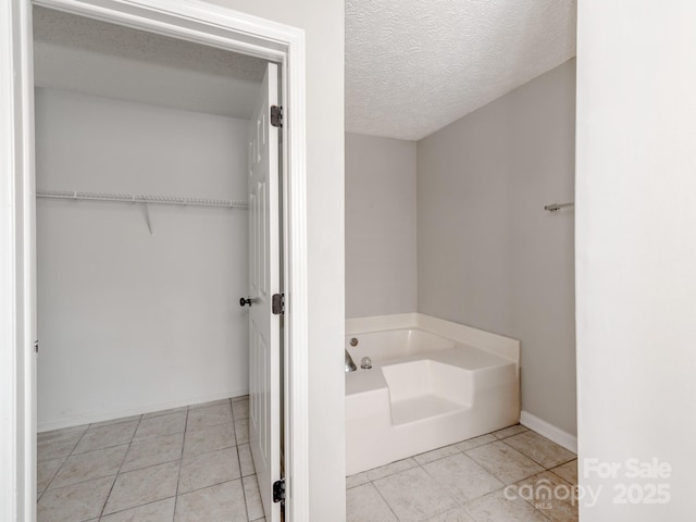 bathroom featuring a washtub, tile patterned floors, and a textured ceiling