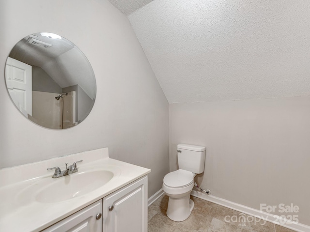 bathroom with vanity, toilet, vaulted ceiling, and a textured ceiling