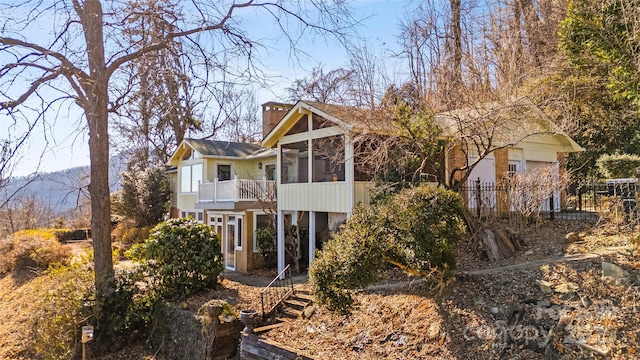 rear view of house featuring a balcony, a sunroom, and a mountain view