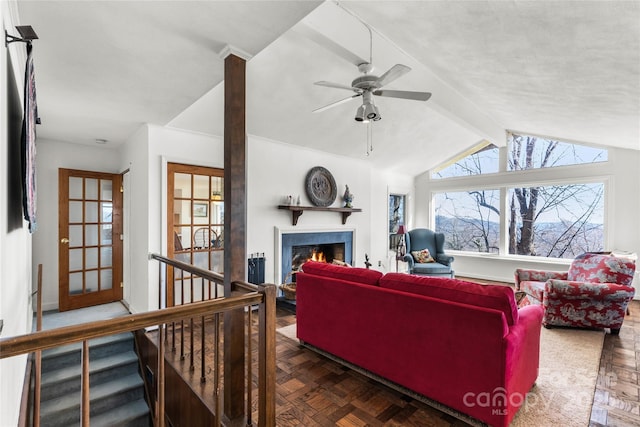 living room featuring a warm lit fireplace, ceiling fan, and lofted ceiling with beams