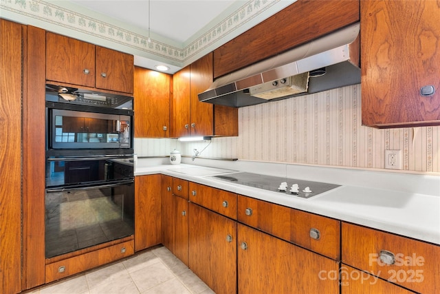 kitchen featuring light countertops, ventilation hood, black appliances, brown cabinetry, and wallpapered walls