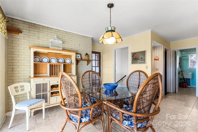 dining space with crown molding, brick wall, and light tile patterned floors