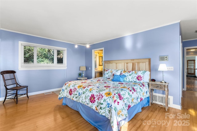 bedroom featuring ornamental molding, wood finished floors, visible vents, and baseboards